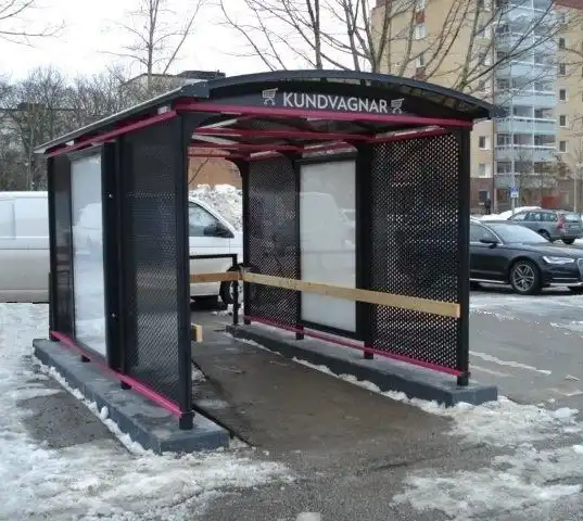 Schwarz-rote Überdachung für Einkaufswagen nahe einer Straße, auf der Schnee liegt.